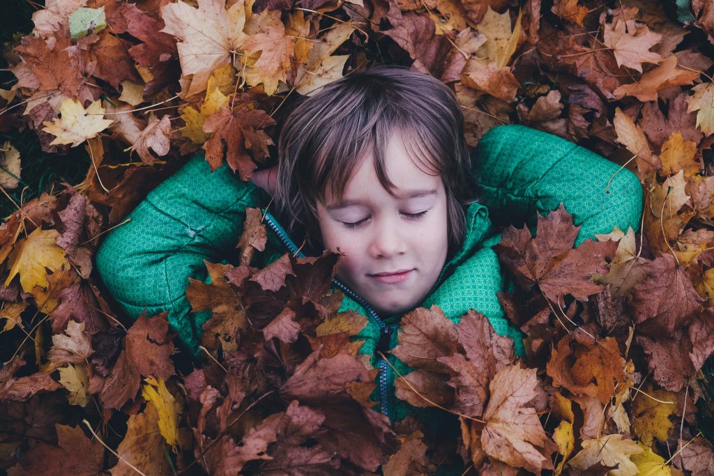 Child laying in leaves