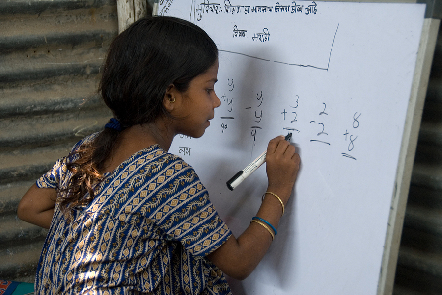 Migrant girl writing math problem