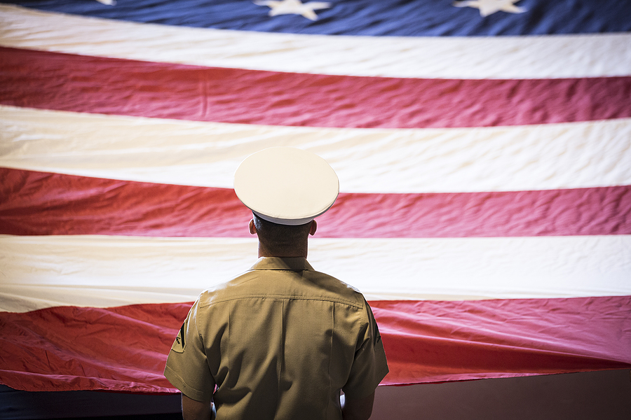 Military member standing before US flag